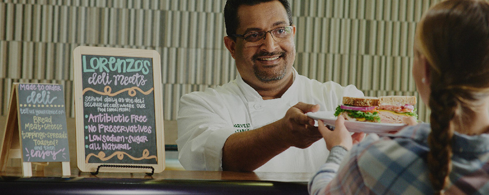 chef smiling while serving food to student